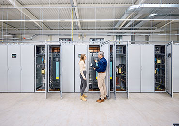 Zwei Mitarbeiter stehen vor Schaltschrank